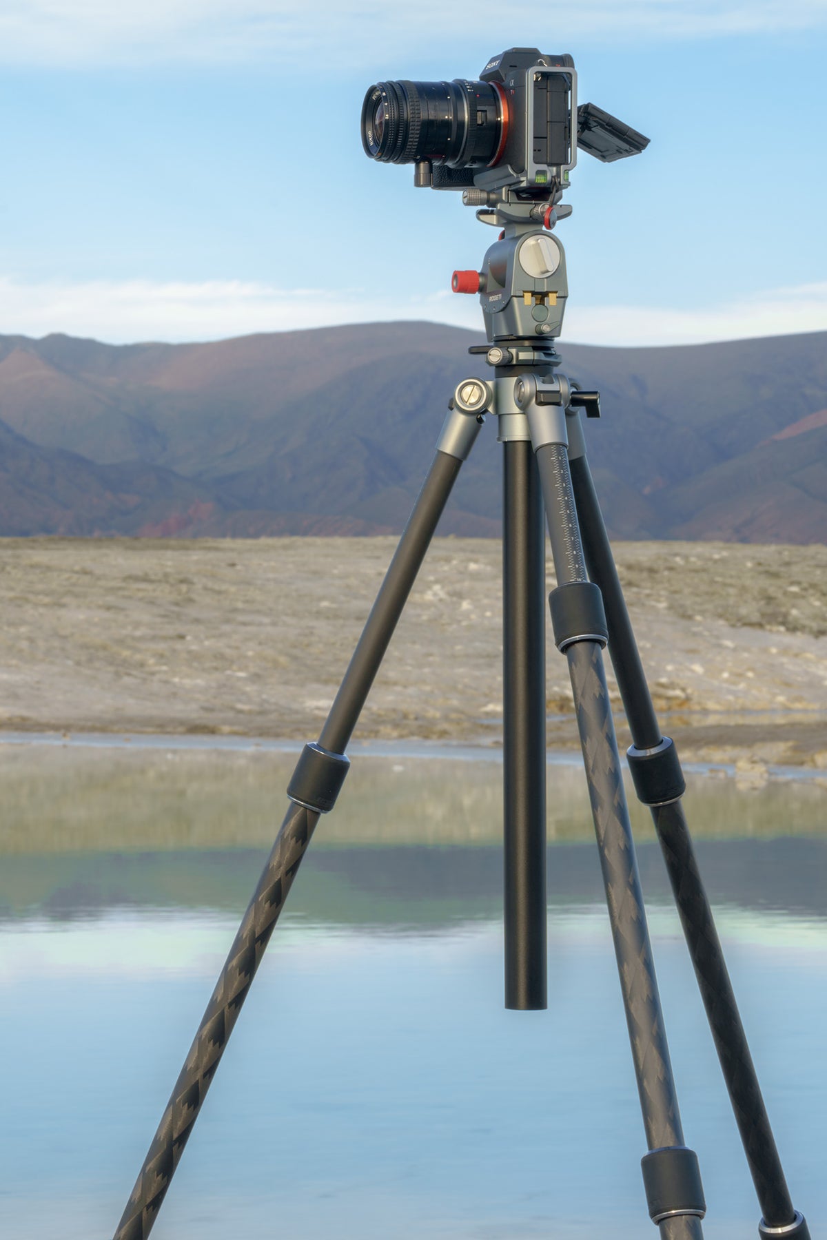 A Sony camera mounted on ROGETI RG-1 gear head and T32 Lite Plus tripod, set against a scenic background of a lake and mountains.